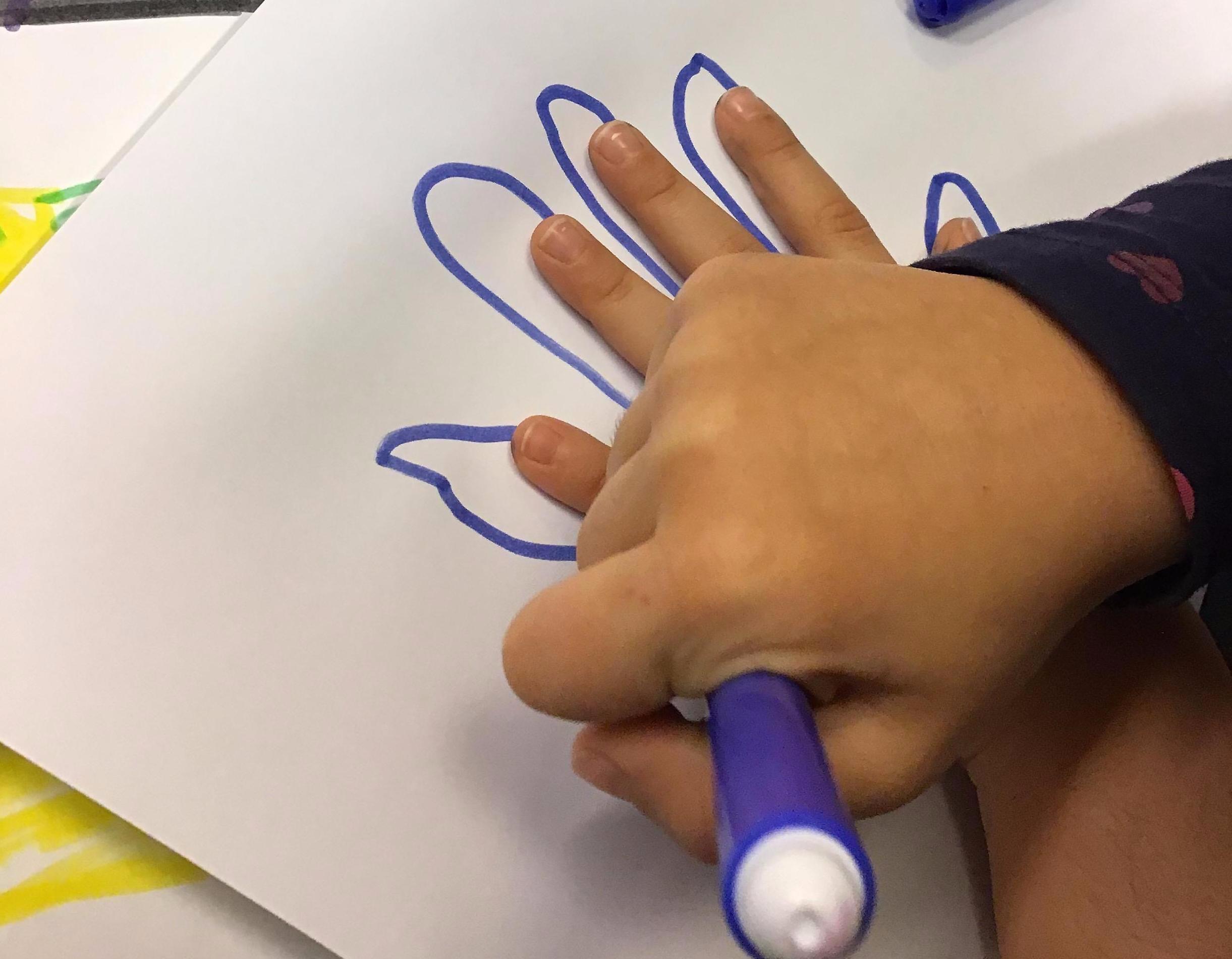 Ett barn ritar av sin hand.