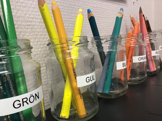 Sorterade färgpennor i glasburkar