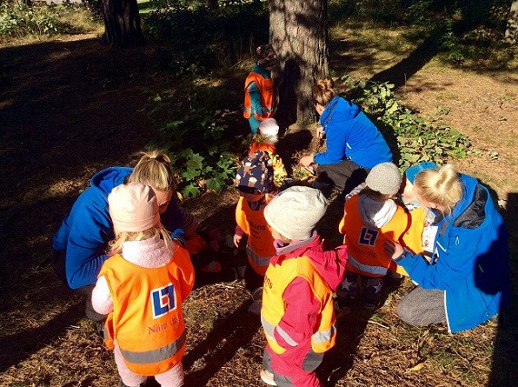 Pedagoger och barn utforskar småkryp i skogen
