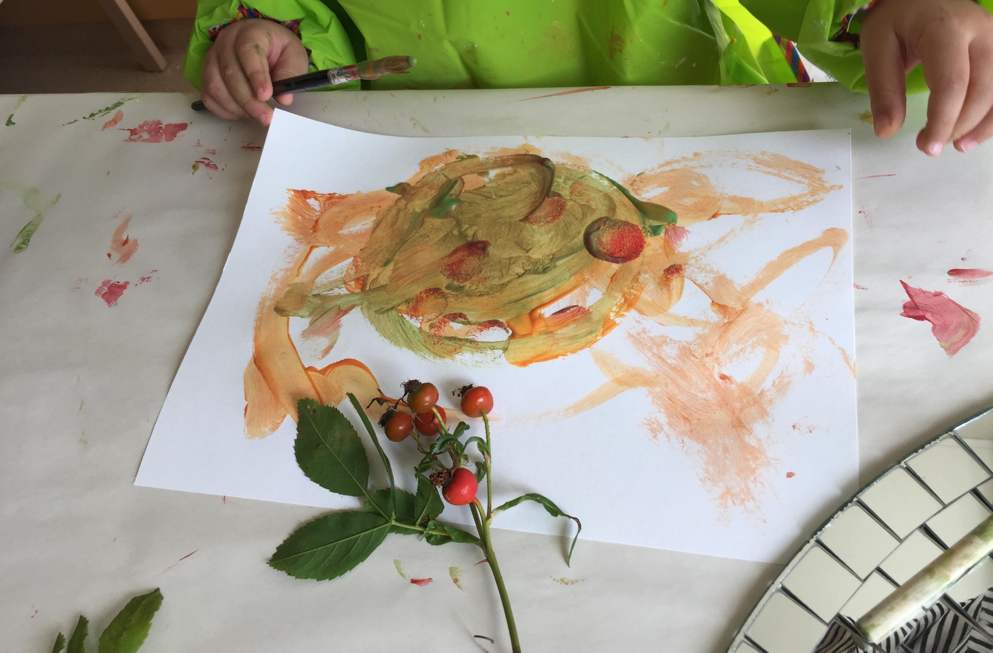 Ett barn målar av en nyponkvist.
