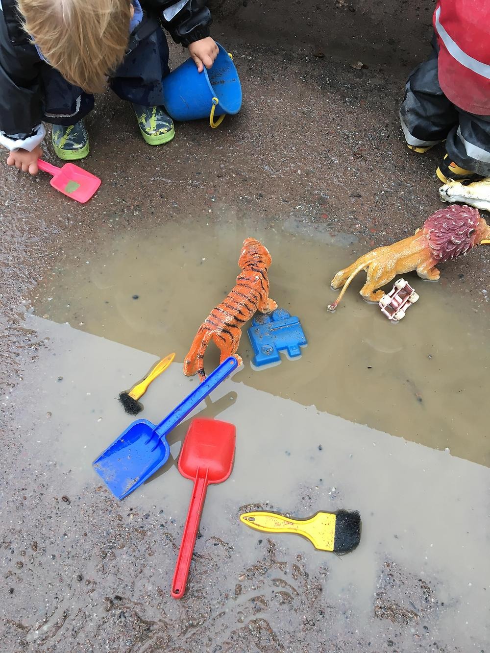 Barn leker med spadar och tiger i en vattenpöl