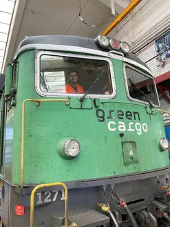 En studerande sitter i ett grönt tåg. Studiebesök på Systemteknikerutbildningen