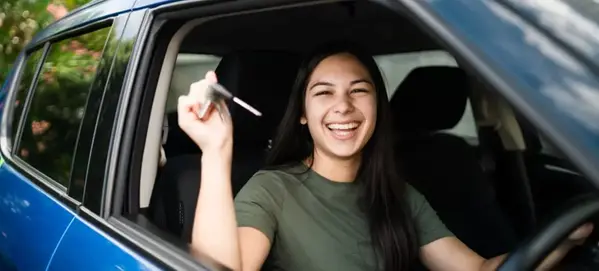 Glad tjej sitter i bilen med bilnyckel i handen